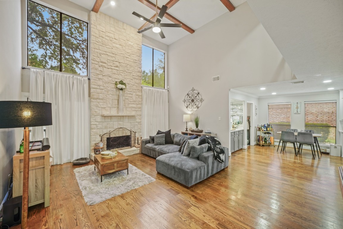 15831 Ridge Park Drive Houston, TX 77095 - Photo 3 of 26 This spacious living area features high ceilings with wooden beams, a stunning stone fireplace, and large windows that provide ample natural light. The open layout flows into a cozy dining area and a modern kitchen, all with warm hardwood flooring.
