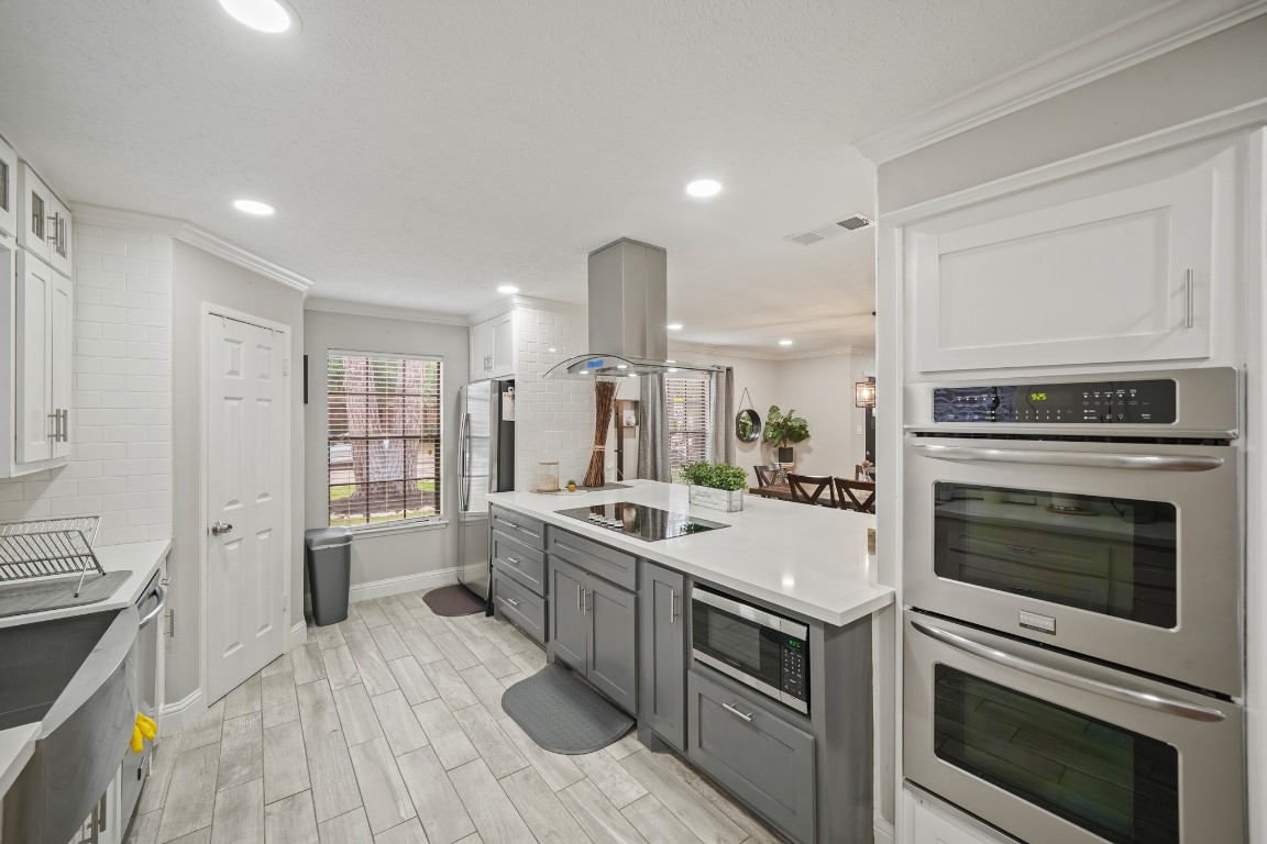 15831 Ridge Park Drive Houston, TX 77095 - Photo 26 of 26 This modern kitchen features sleek, stainless steel appliances, a large island with cooktop, and ample cabinetry. Natural light streams through a window, highlighting the open floor plan that flows into a dining area. Perfect for entertaining and everyday living.
