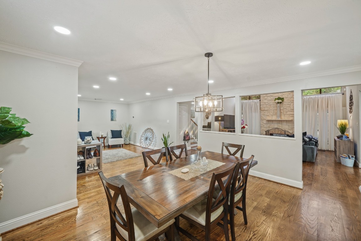 15831 Ridge Park Drive Houston, TX 77095 - Photo 5 of 26 This photo showcases a spacious, open-concept living and dining area with elegant hardwood floors and modern lighting. The room is bright and inviting, featuring neutral walls, a stylish chandelier over the dining table, and ample natural light from large windows.