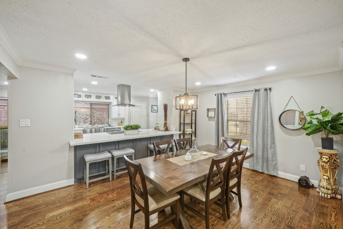 15831 Ridge Park Drive Houston, TX 77095 - Photo 6 of 26 This photo showcases a bright and open dining area connected to a modern kitchen with a large island. Hardwood floors, recessed lighting, and ample natural light enhance the welcoming atmosphere.