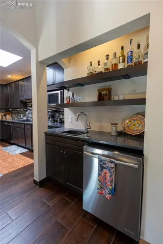 a kitchen with granite countertop lots of stainless steel appliances and wooden floor