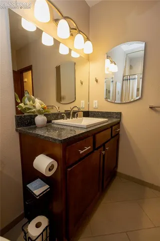 a bathroom with a granite countertop sink and a mirror