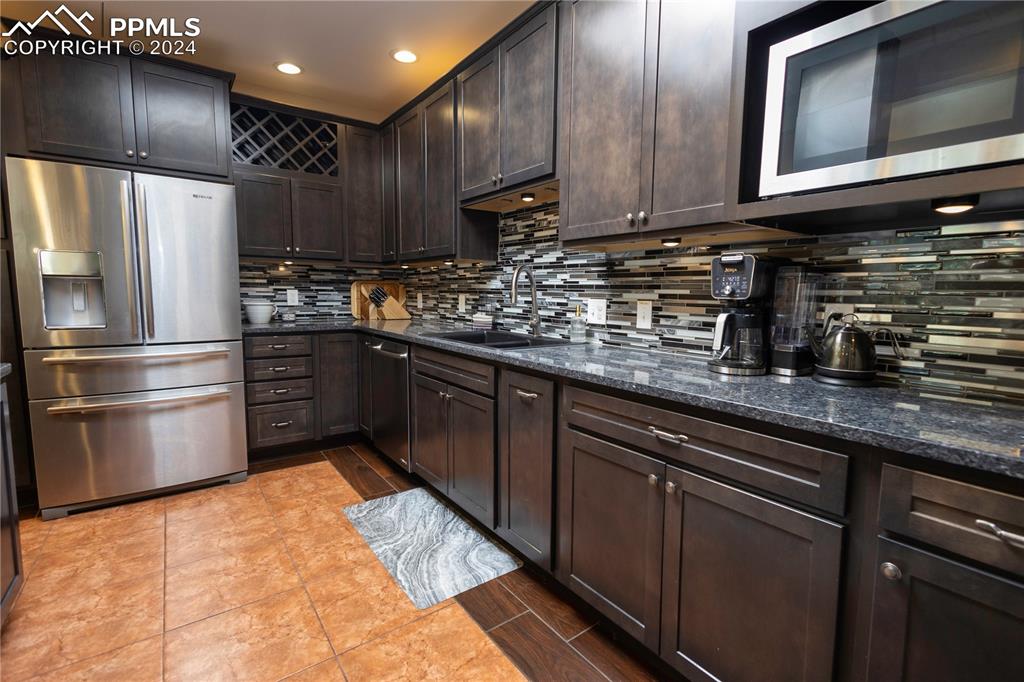 3123 Broadmoor Valley Road, Unit D Colorado Springs, CO 80906 - Photo 7 of 38 a kitchen with kitchen island granite countertop wooden cabinets stainless steel appliances and a sink