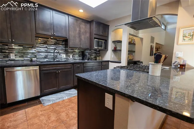 a kitchen with stainless steel appliances granite countertop a sink a stove and a microwave
