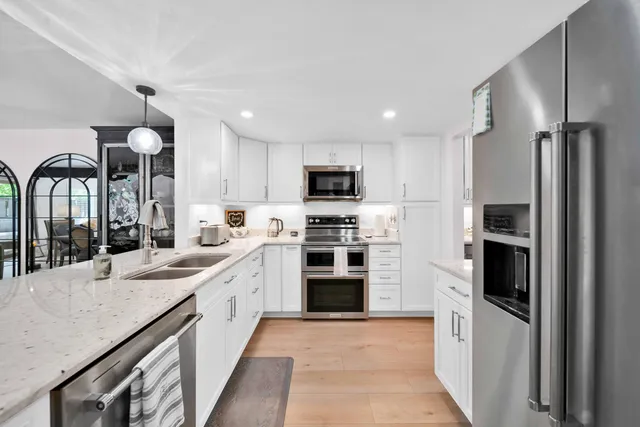 a kitchen with cabinets stainless steel appliances and wooden floor