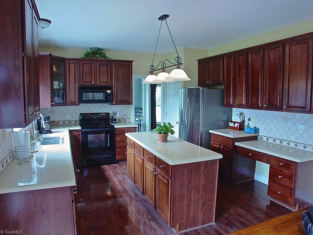 711 Number Ten Way Oak Ridge, NC 27310 - Photo 2 of 25 Big kitchen with hardwood floors, island and desk area. Solid surface counters and tile backsplash. Plenty of counter space for cooking and entertaining.