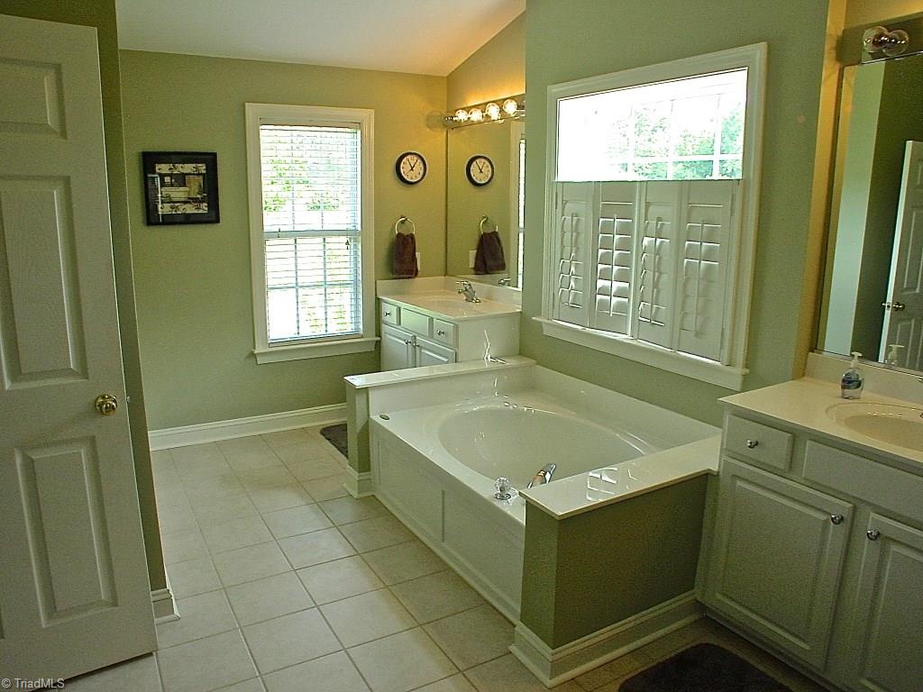 711 Number Ten Way Oak Ridge, NC 27310 - Photo 21 of 25 Master bath has Separate his and hers vanities, Garden Tub and separate shower. The room has great windows that brighten the space.
