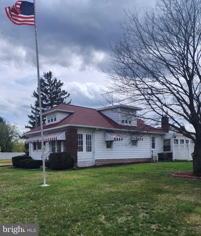 a view of a house with a small yard and a large parking space