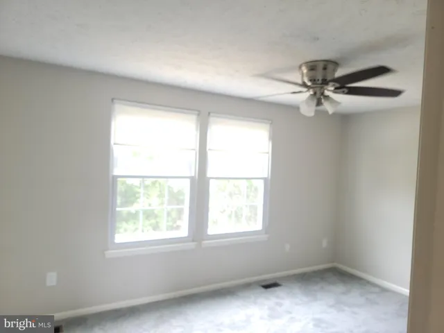 an empty room with a window and a fan
