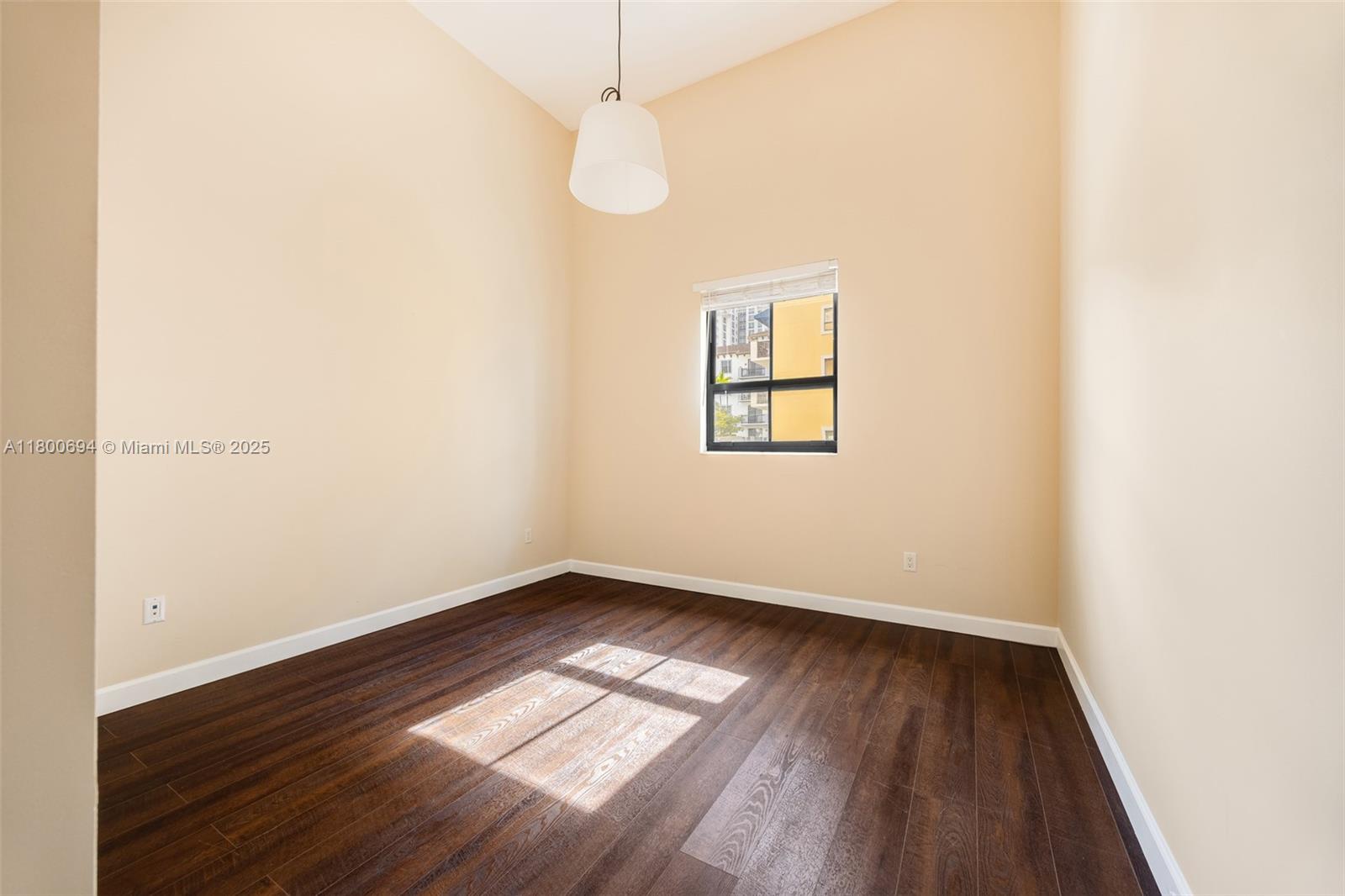 8395 Southwest 73rd Avenue, Unit 320 Miami, FL 33143 - Photo 7 of 18 an empty room with wooden floor chandelier fan and windows