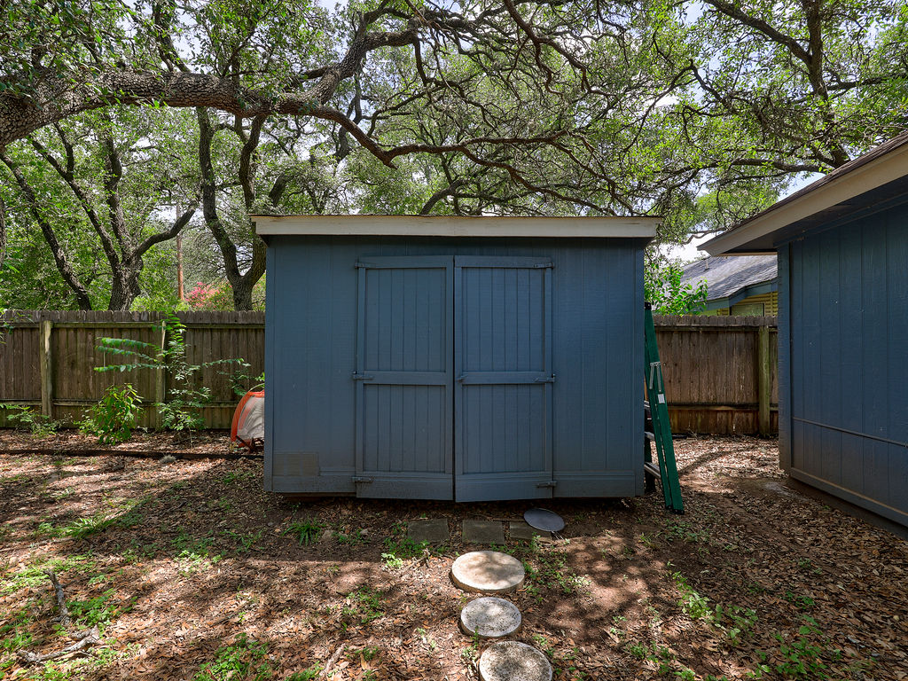 5842 Secrest Drive Austin, TX 78759 - Photo 6 of 40 A quaint storage shed nestled beneath the mature trees offers practical outdoor utility.