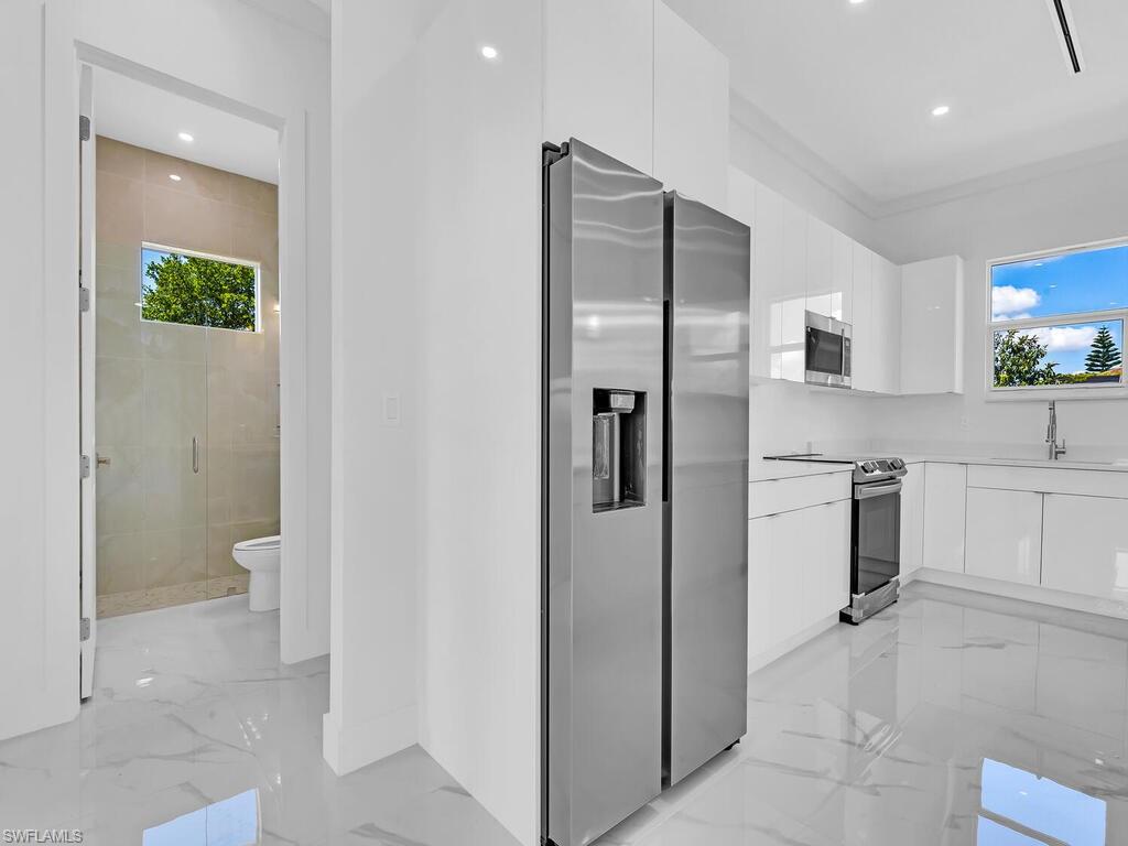 6006 Stratton Road Fort Myers, FL 33905 - Photo 10 of 27 Kitchen featuring a healthy amount of sunlight, white cabinetry, sink, and appliances with stainless steel finishes