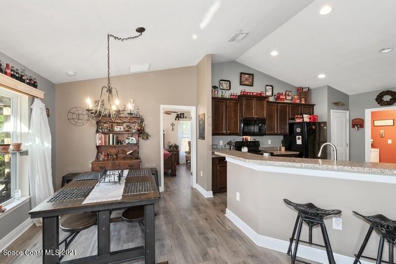 1808 Holbrook Road Northwest Palm Bay, FL 32907 - Photo 4 of 28 a kitchen with stainless steel appliances kitchen island granite countertop a dining table chairs and a refrigerator