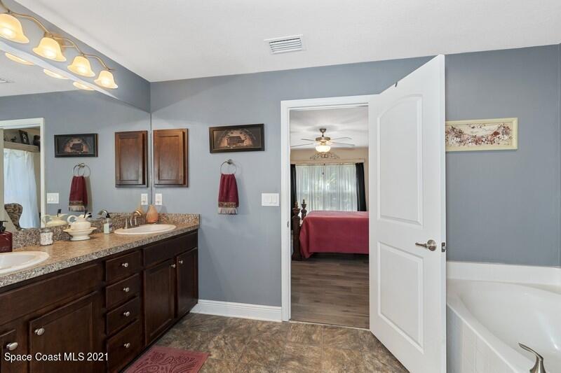 1808 Holbrook Road Northwest Palm Bay, FL 32907 - Photo 10 of 28 a spacious bathroom with a double vanity sink a mirror and a bathtub
