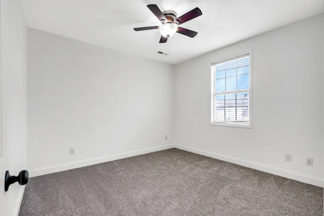 an empty room with a window and a ceiling fan