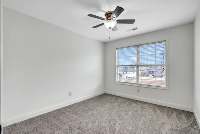 an empty room with a window and a fan