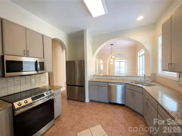 a kitchen with stainless steel appliances granite countertop a stove a sink and a microwave