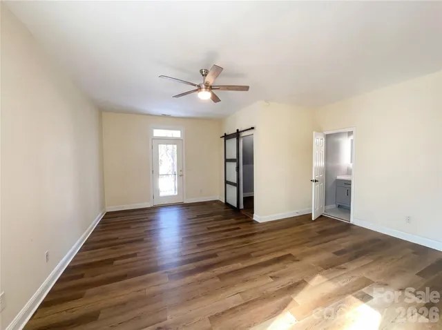 a view of an empty room with window and wooden floor