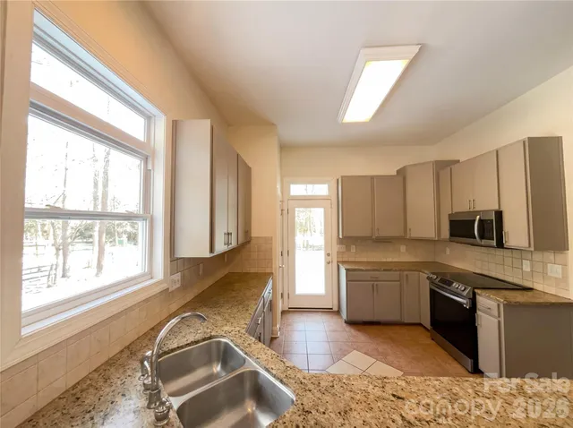 a large kitchen with kitchen island granite countertop a stove top oven a sink a dining table and chairs