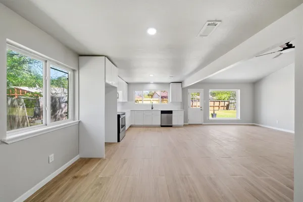 a view of an empty room with a window and wooden floor