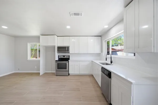 a large kitchen with stainless steel appliances granite countertop a stove a sink and a refrigerator