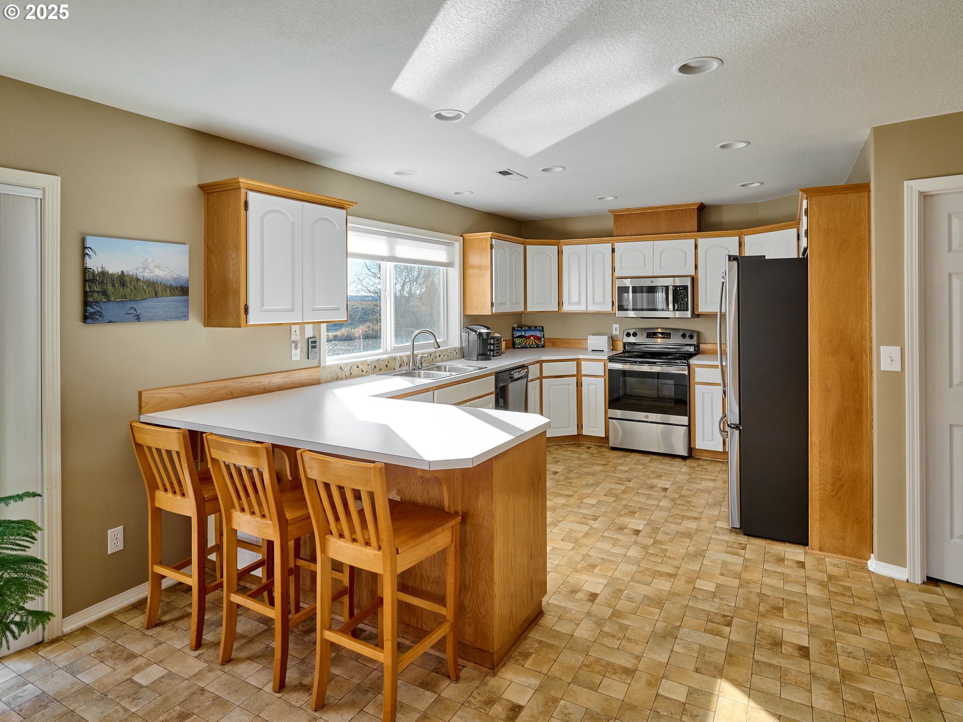 920 Hermanson Street Woodburn, OR 97071 - Photo 11 of 48 a kitchen with stainless steel appliances granite countertop a table chairs sink refrigerator and microwave