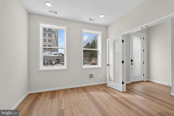 an empty room with wooden floor and windows