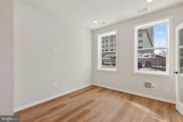 a view of an empty room with a window and wooden floor