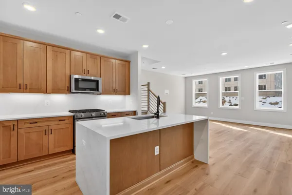 a kitchen with stainless steel appliances granite countertop a stove top oven a sink dishwasher and a refrigerator with wooden floor