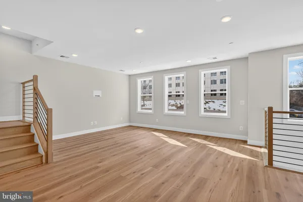 an empty room with wooden floor and windows