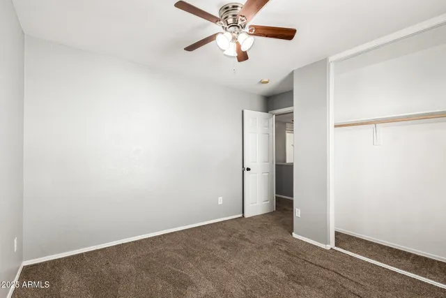 an empty room with closet and a chandelier fan