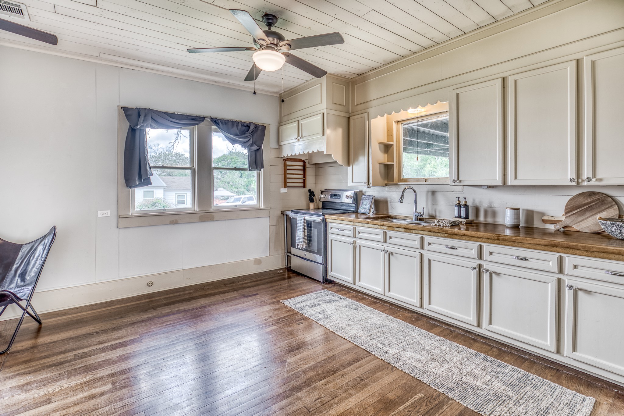 404 West Main Street Bellville, TX 77418 - Photo 9 of 36 a kitchen with granite countertop a stove a sink and white cabinets with wooden floor