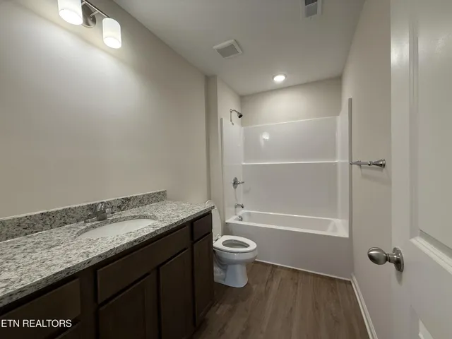 a bathroom with a granite countertop sink a toilet and shower