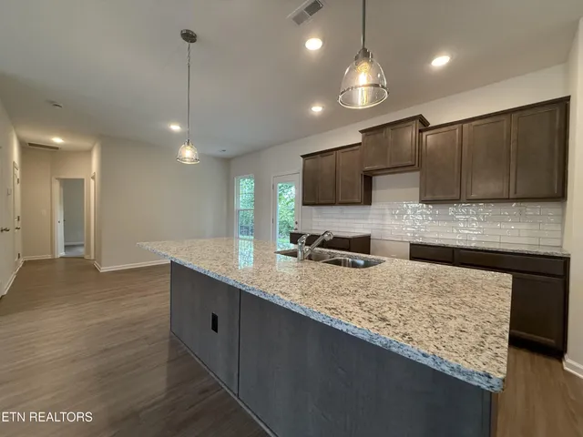 a kitchen with granite countertop a sink a counter top space appliances and cabinets