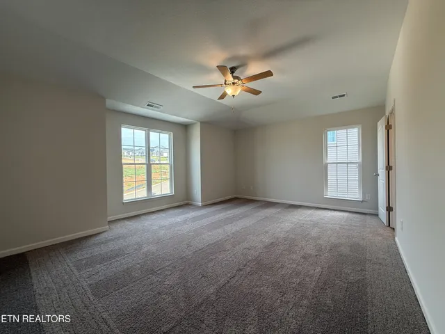 an empty room with windows and ceiling fan