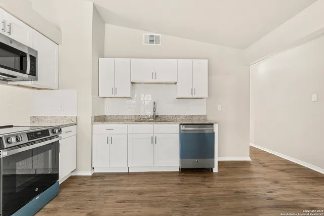 a kitchen with granite countertop white cabinets and stainless steel appliances