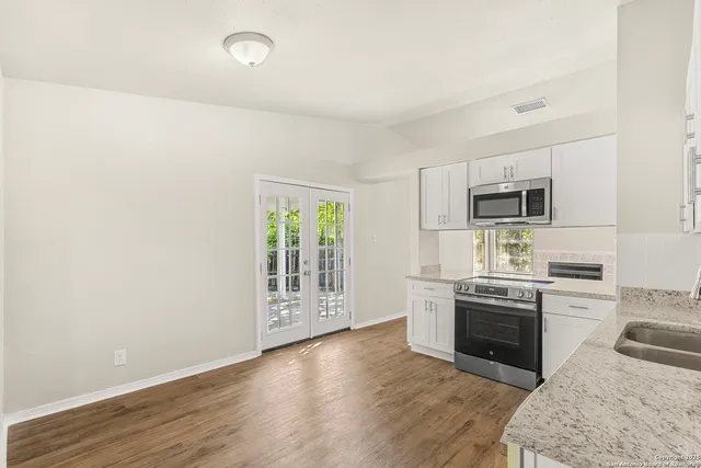 a kitchen with stainless steel appliances granite countertop a stove top oven a sink and dishwasher a refrigerator with wooden floor