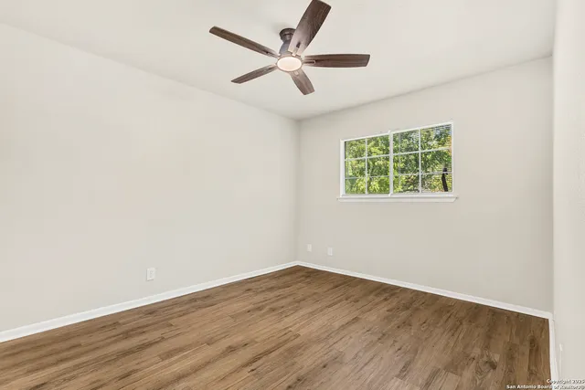 an empty room with wooden floor and ceiling fan