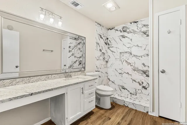 a bathroom with a granite countertop toilet a sink and a shower
