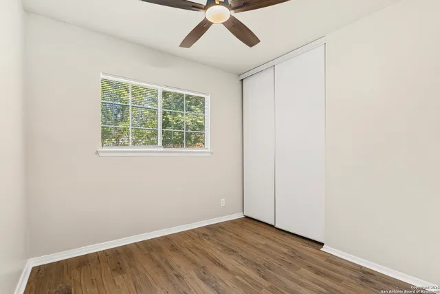 an empty room with a window and a ceiling fan