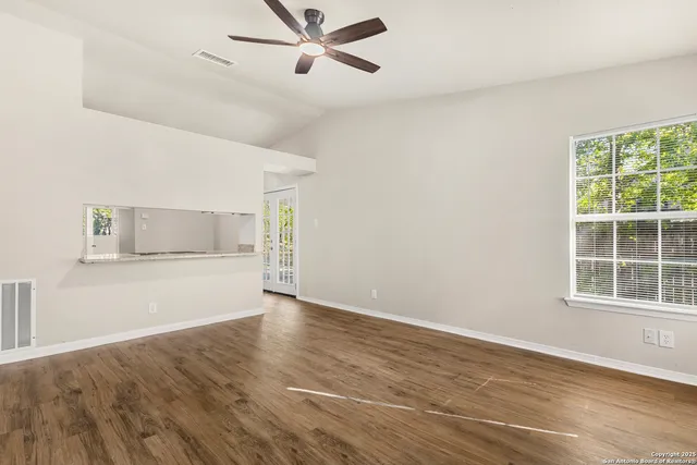 a view of an empty room with a window and wooden floor