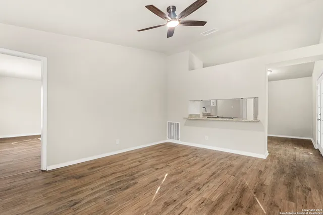 a view of empty room with wooden floor and ceiling fan