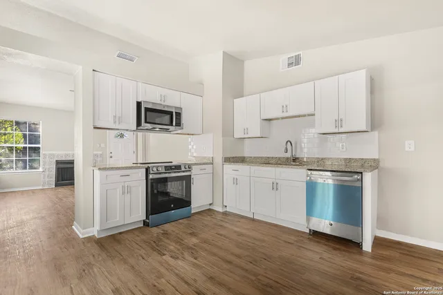a kitchen with granite countertop white cabinets and stainless steel appliances