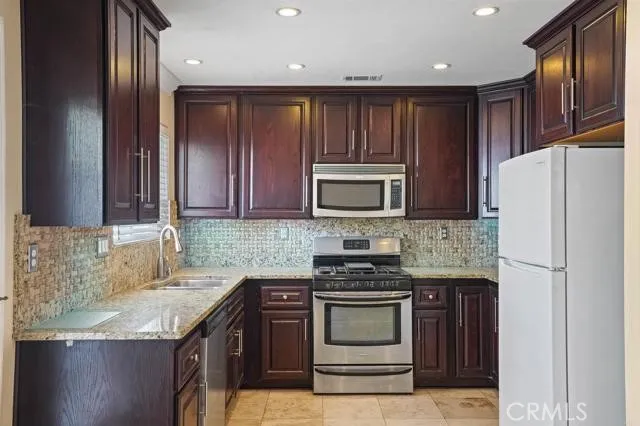 a kitchen with granite countertop stainless steel appliances and wooden cabinets