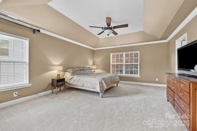 a bedroom with a bed flat screen tv and windows