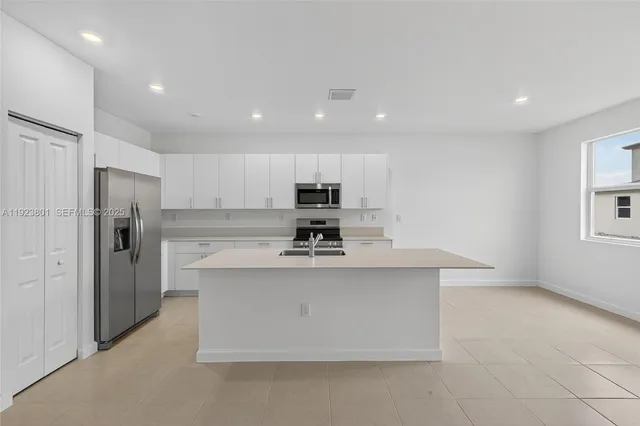 a view of kitchen with stainless steel appliances granite countertop a stove top oven a refrigerator and a cabinets