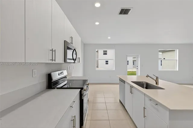 a large white kitchen with white stainless steel appliances