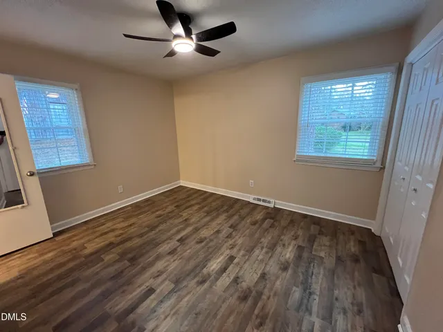 a view of an empty room with wooden floor and a window
