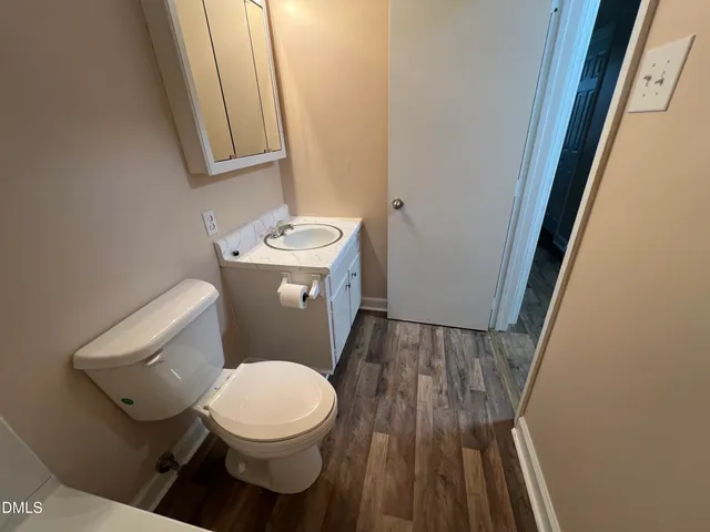 a white toilet sitting next to a wooden floor