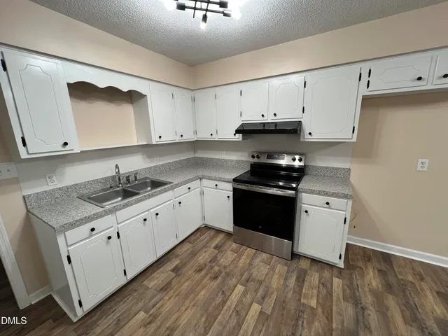 a kitchen with granite countertop white cabinets and black appliances